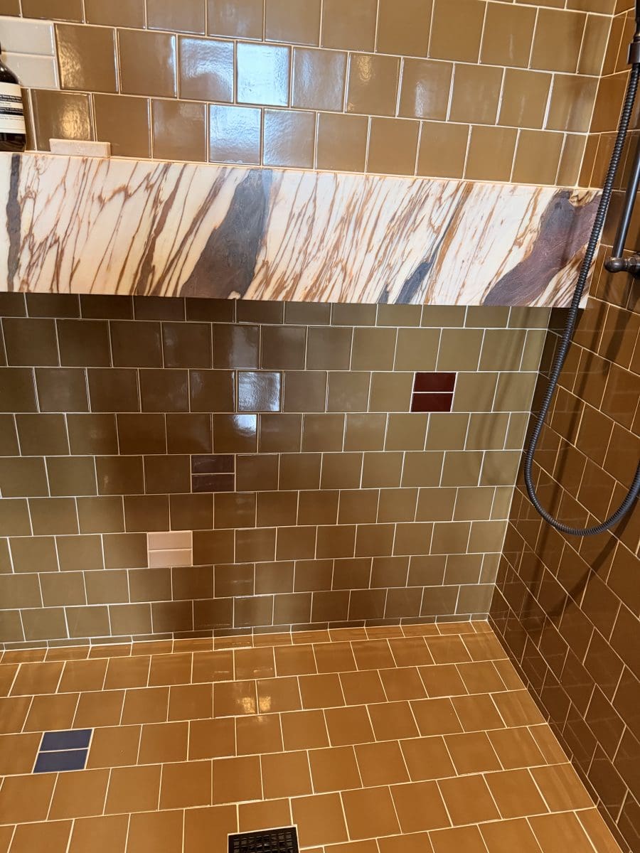 Tile sample swatches arranged on a shower wall and floor showing color and pattern options