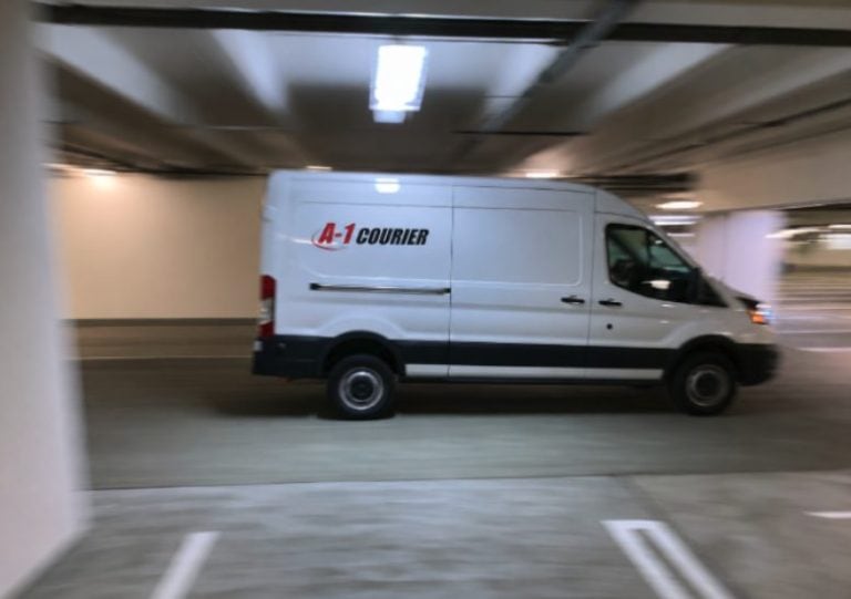 A-1 Courier delivery van in motion in parking garage.